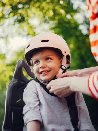 Mutter zieht ihrem Kind den Fahrradhelm an